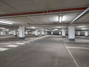 Eine mehrgeschossige Parkgarage mit Betonpfeilern, Neonbeleuchtung und deutlichen Fahrbahnmarkierungen.