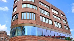 Een modern gebouw met een gebogen gevel, grote ramen en een spiegelend glazen gedeelte.