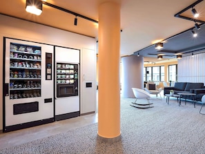 Eine moderne Lobby mit Verkaufsautomaten, Sitzgelegenheiten und einer großen Säule.