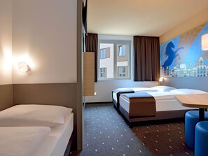 Een hotelkamer met twee bedden, een stadslandschap muurschildering, een raam met gordijnen en een kamerkleed met dessin.