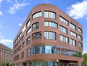 Un immeuble à plusieurs étages doté d’une façade incurvée, de grandes fenêtres et d’une entrée en verre.