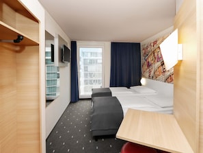 A hotel room with a bed, bedside table, TV, and a window with curtains. - B&B Hotel Berlin-Alexanderplatz (Berlin)