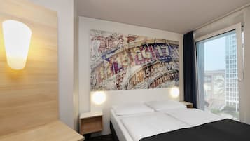Una habitación de hotel con cama, una mesita de noche de madera, una lámpara de pared y una obra de arte abstracta de gran tamaño.