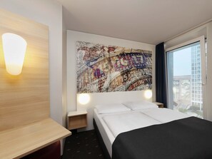 A hotel room with a bed, a wooden nightstand, a wall-mounted lamp, and a large abstract artwork. - B&B Hotel Berlin-Alexanderplatz (Berlin)