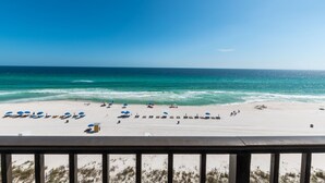 A beach with rows of sun loungers and umbrellas, a clear blue sky, and the ocean.