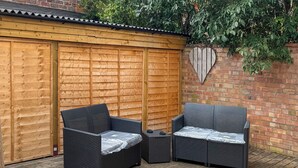 Un espace patio aménagé avec deux canapés en osier, une petite table et une terrasse en bois.