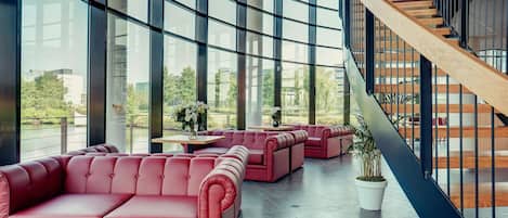 Un intérieur moderne avec de grandes fenêtres, un escalier en colimaçon et des espaces de détente aux couleurs rouge.