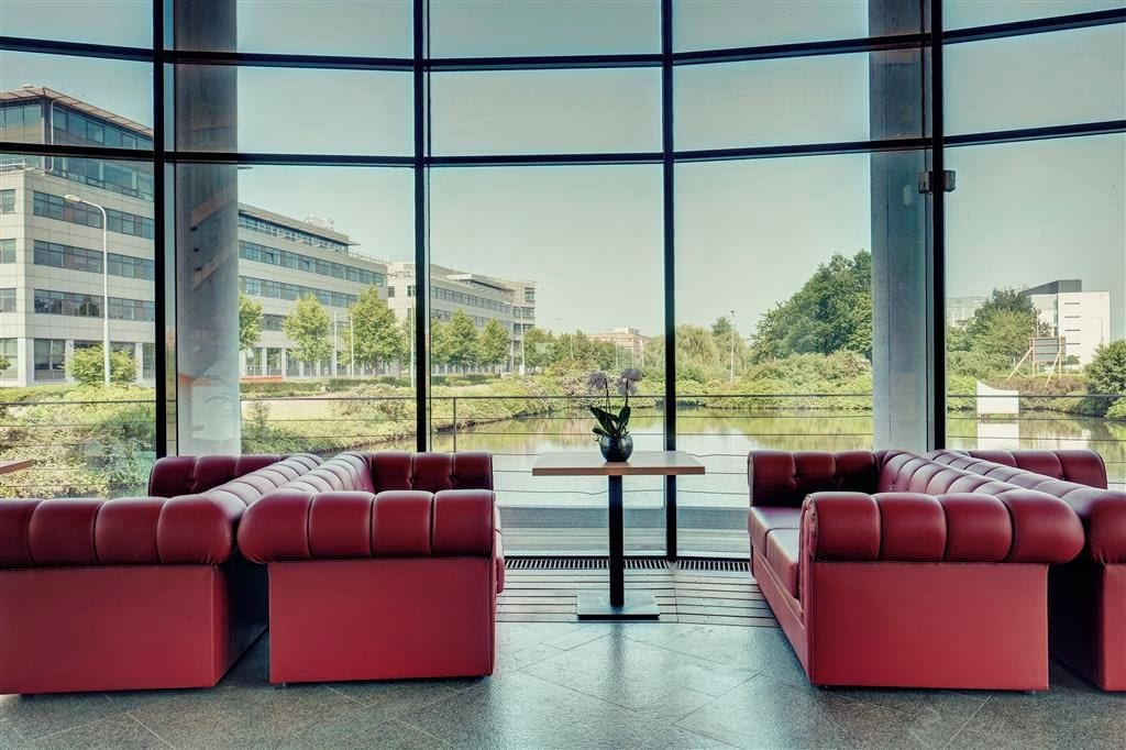 Un interior moderno con ventanas amplias, asientos rojos y una pequeña mesa.