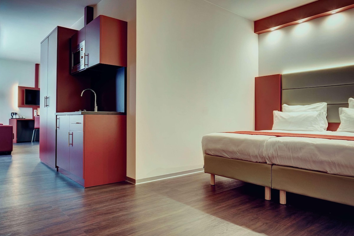 Une chambre d’hôtel moderne équipée d’un lit, d’une kitchenette et d’un téléviseur.