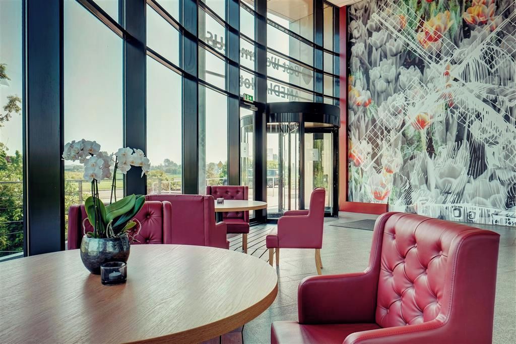 Un interior moderno con una mesa redonda, sillas tapizadas en rojo y un gran ventanal con vistas al exterior.