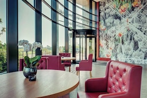Een modern interieur met een ronde tafel, rode beklede stoelen en een groot raam met uitzicht op het omliggende landschap.