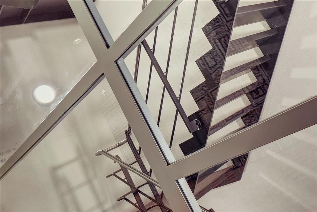 A modern staircase with glass railings and a geometric pattern on the steps.