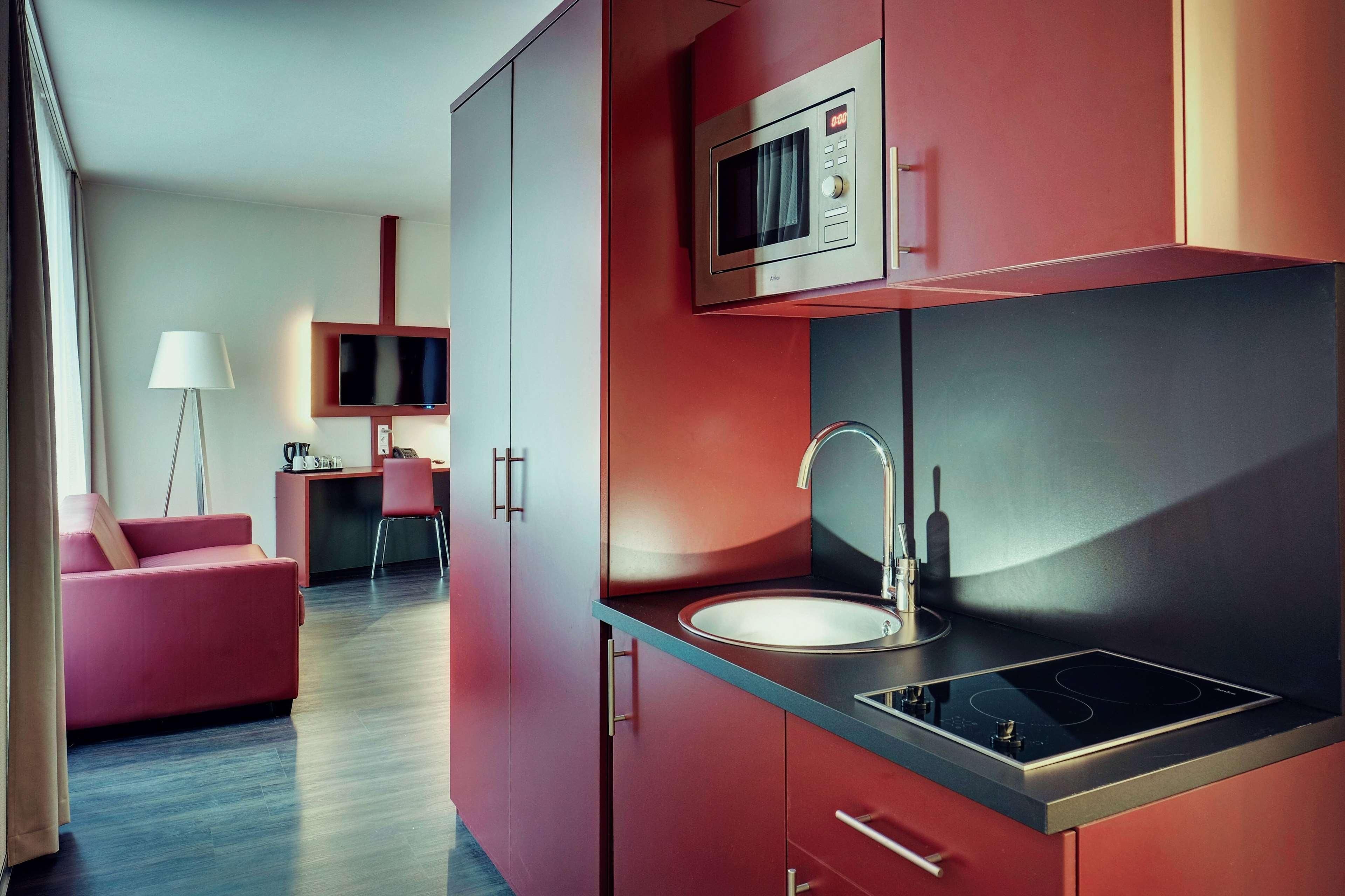 Una cocina compacta con microondas, lavamanos y electrodomésticos modernos.