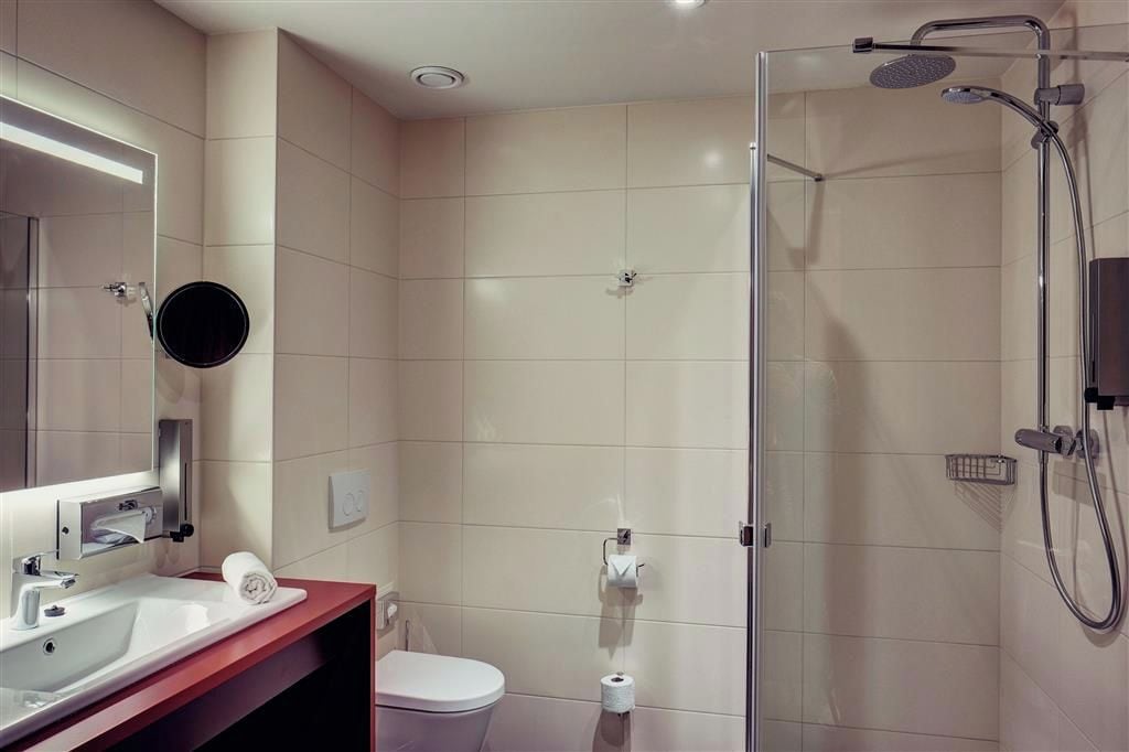 A modern bathroom with a glass shower enclosure, a white toilet, and a vanity with a mirror.