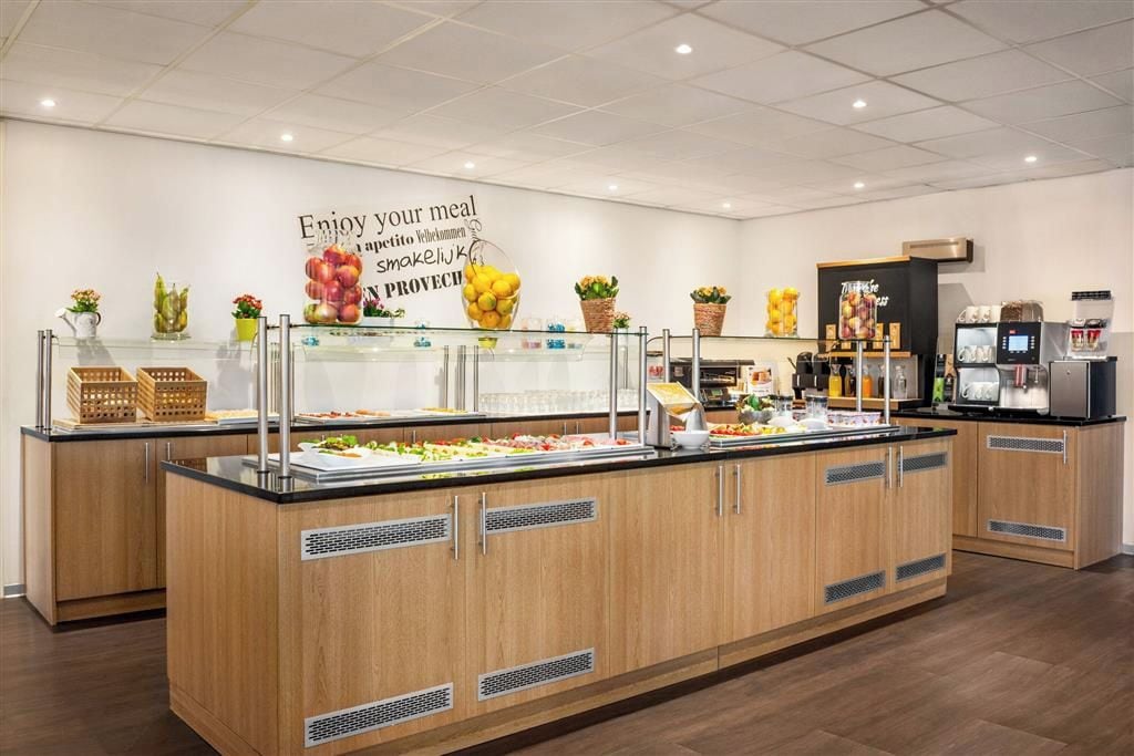 A buffet area with various food items and a sign encouraging guests to enjoy their meal.