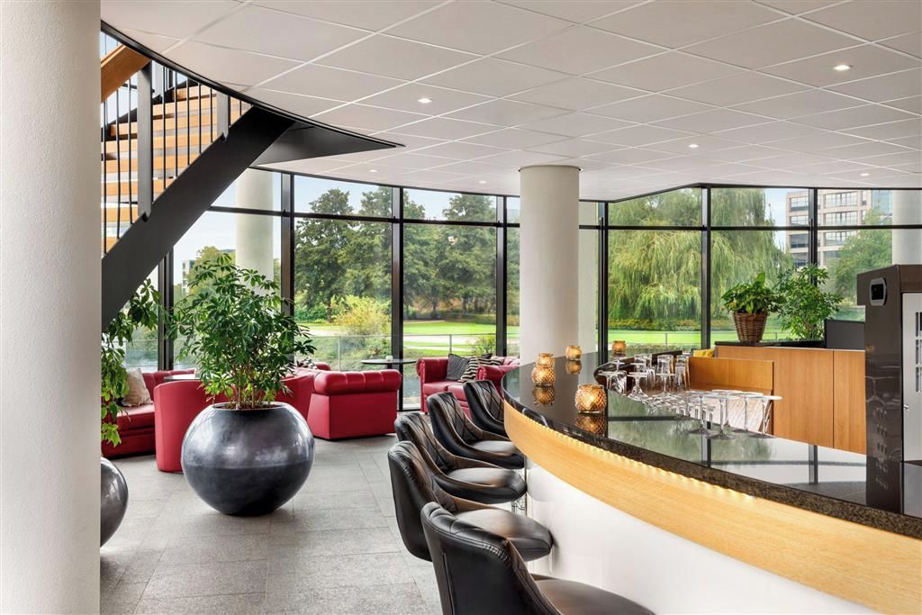 A modern lobby with a curved reception desk, leather seating, and large windows offering a view of the outdoors.