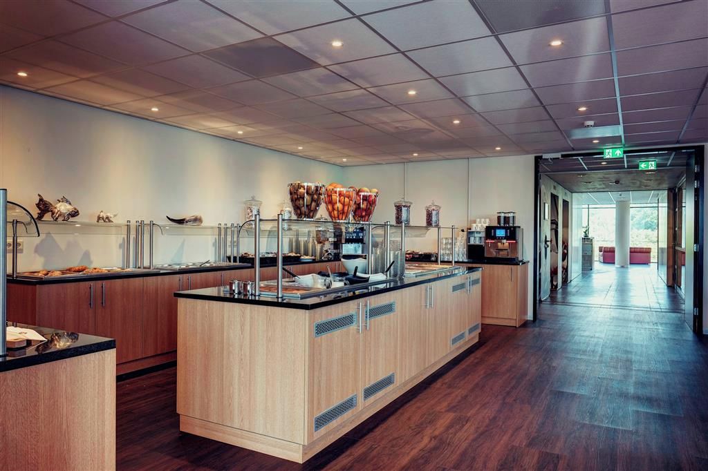 A modern kitchen area with a central island, wooden cabinets, and a glass display case with food items.