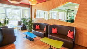Un lobby moderno con sofás de cuero, una mesa de centro y un espejo grande que refleja el interior.