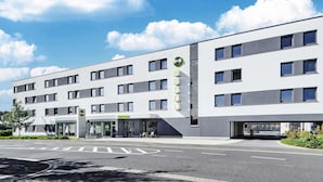 Un hotel moderno con una recepción, varios pisos y cielo despejado.