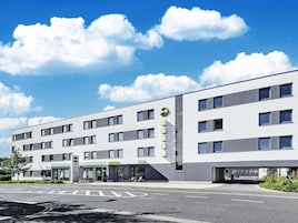 Ein modernes Hotel mit Empfangsbereich, mehreren Stockwerken und blauem Himmel.