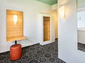 A modern interior with a wooden bench, a red stool, and patterned flooring. - B&B HOTEL Aschaffenburg-Hbf (Aschaffenburg)