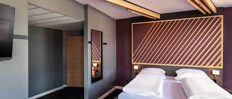 A modern hotel room with a large bed, bedside tables, a flat-screen TV, and a unique geometric wall design.