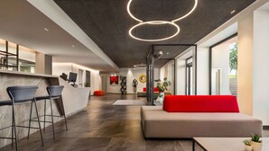 A modern interior with a bar area, seating, and a large window. - Amedia Milano - Trademark Collection by Wyndham (Milan)