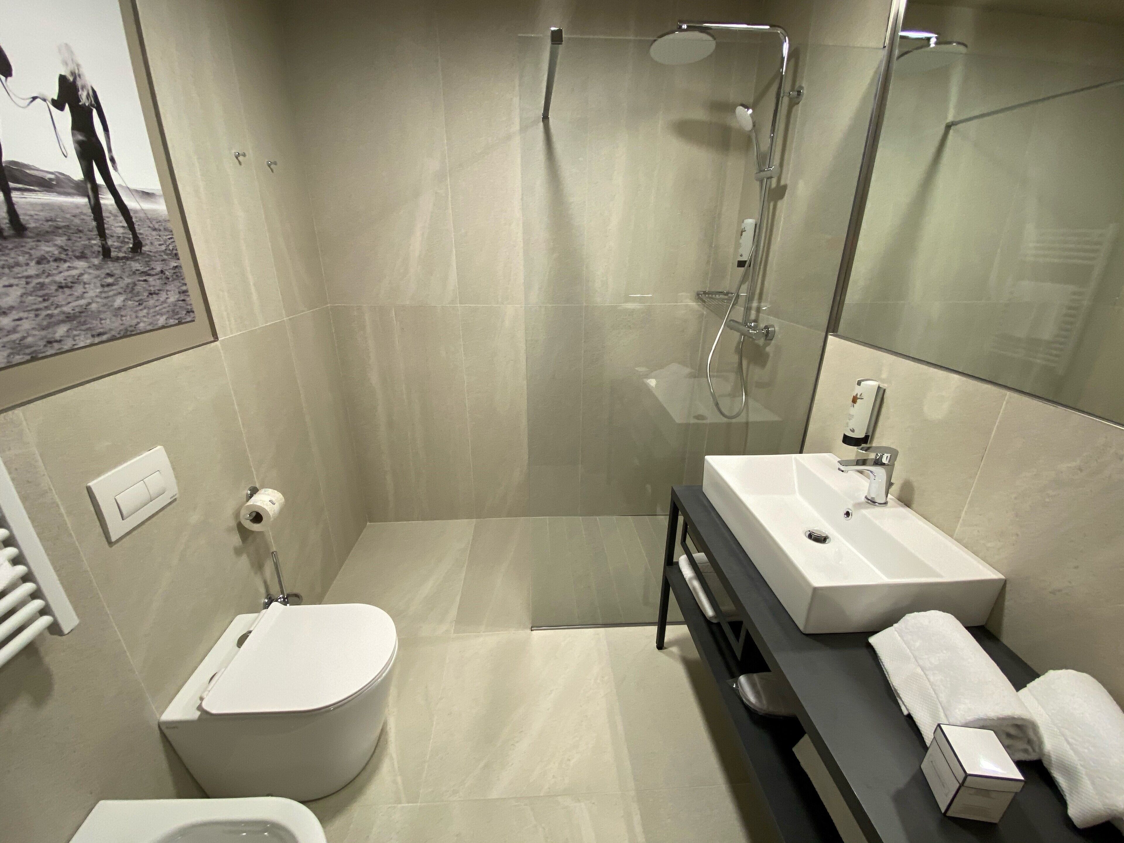 A modern bathroom with a toilet, sink, and shower.