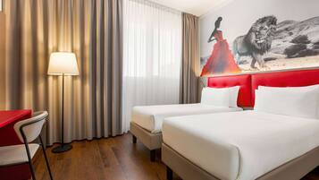 Ein Hotelzimmer mit zwei Betten, einem Schreibtisch, einem Stuhl und einer Lampe.