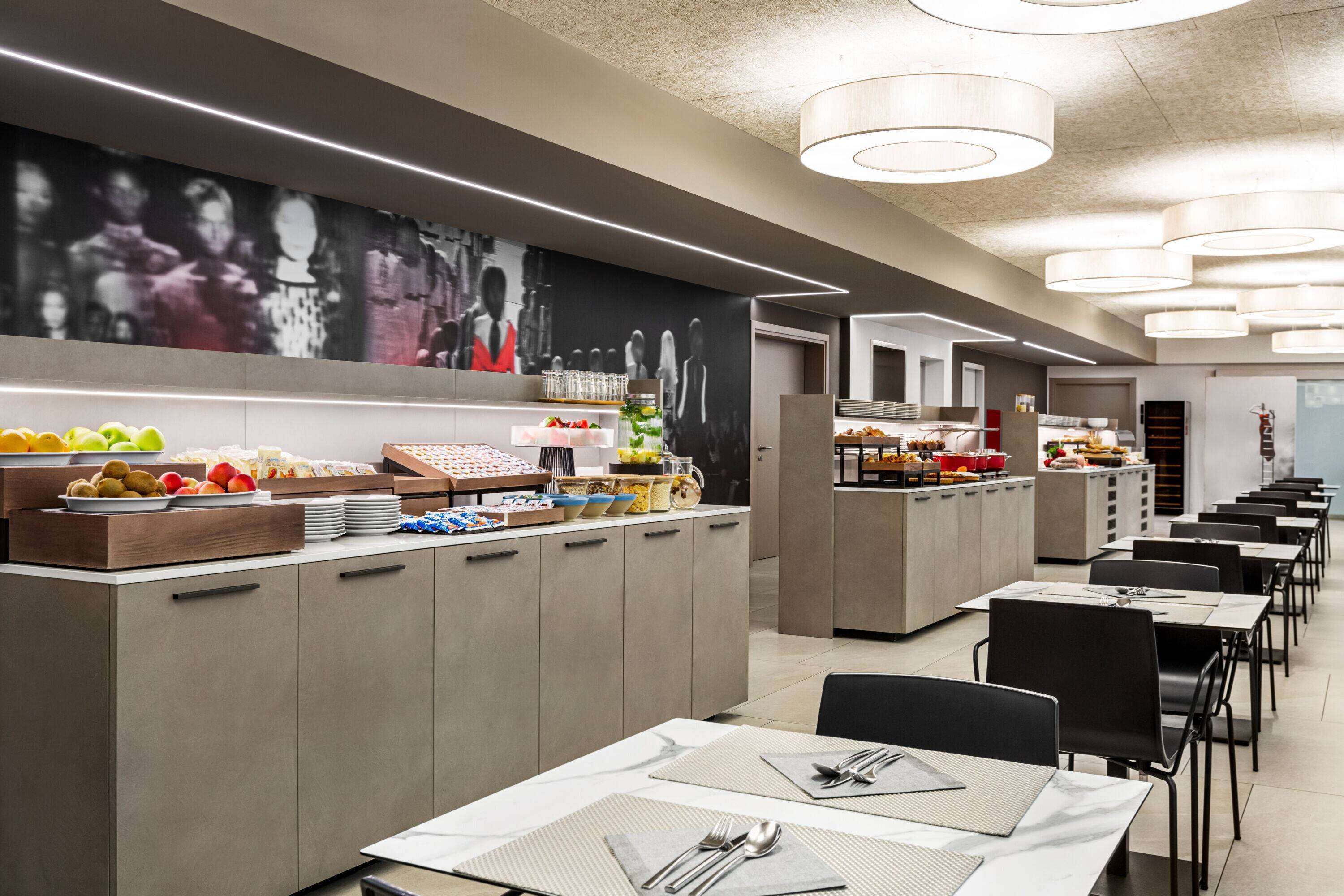 A modern dining area with a buffet setup, including various food items and a seating arrangement with tables and chairs.