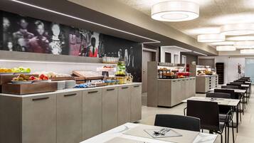 A modern dining area with a buffet setup, including various food items and a seating arrangement with tables and chairs.