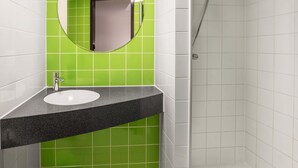 Un baño con lavamanos, espejo y ducha.
