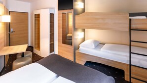 Habitació d'hotel moderna amb un llit superposat, escriptori i armari.