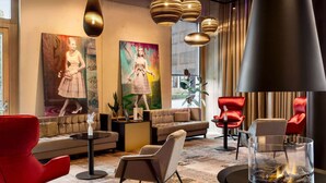 A modern lounge area with a sofa, red chairs, a fireplace, and artwork on the walls. - Radisson Hotel Lustenau (Lustenau)