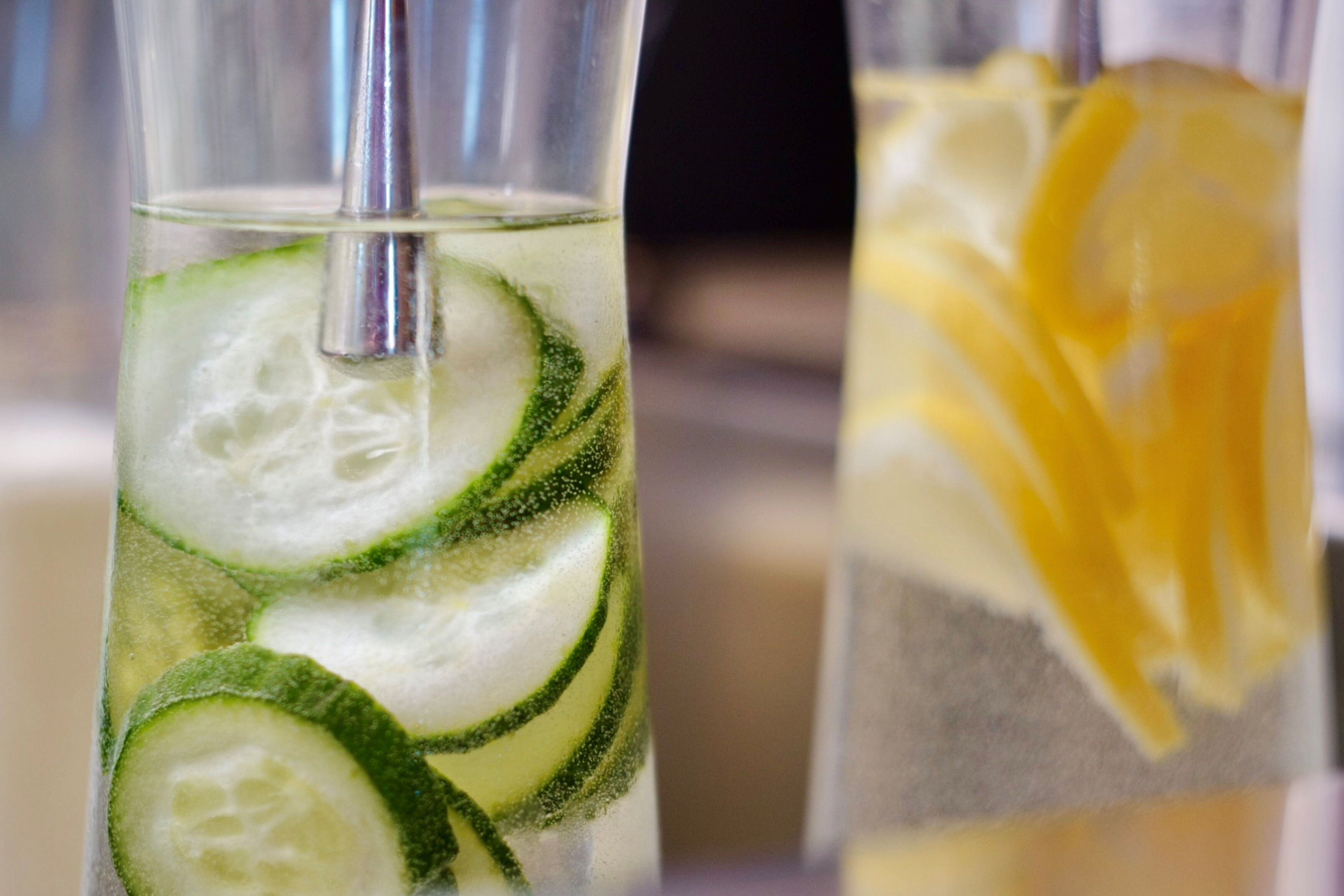 Dos vasos de bebidas con hielo, rodajas de pepino y limón.
