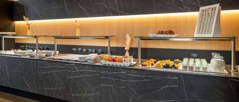 A buffet counter with various food items and a coffee station.