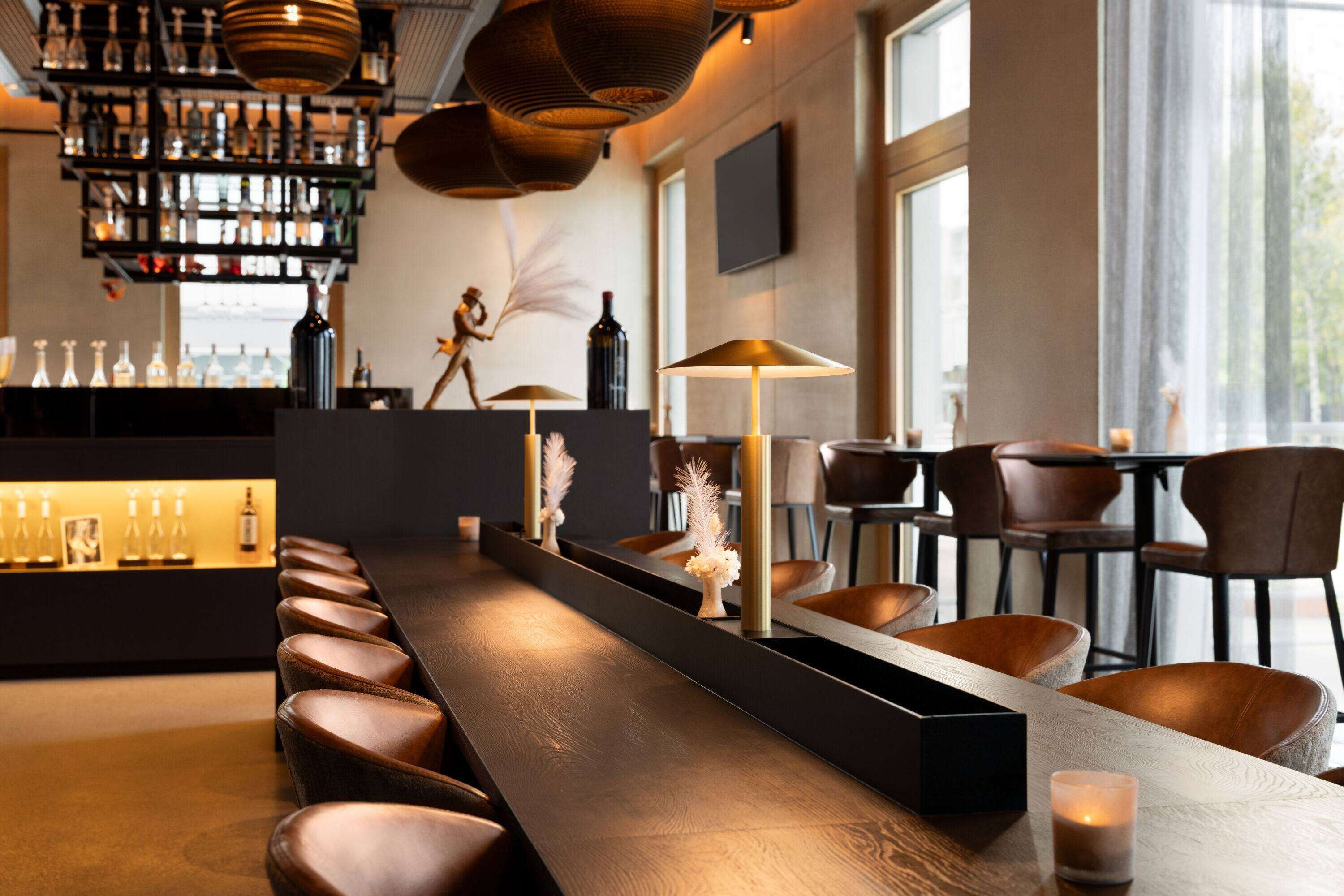 Eine Bar mit einer langen Theke, Ledersesseln und einer Auswahl an Flaschen in Regalen.