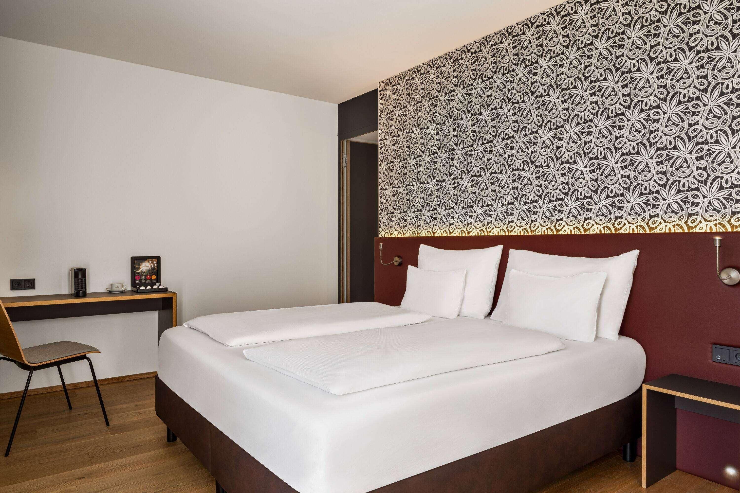 A hotel room with a bed, a desk, and a chair.