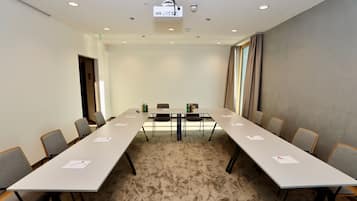 Une salle de conférence avec une longue table, des chaises, un projecteur et un sol recouvert de moquette.