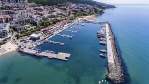 An aerial view of a coastal town with a marina, residential buildings, and a hilly backdrop. - Menada Galateya Apartments (Sveti Vlas)