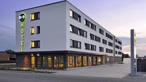 Un hôtel moderne, avec un bâtiment à la façade plate, de nombreuses fenêtres et une entrée bien éclairée.