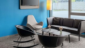 Un salon moderne avec un mur bleu, un téléviseur à écran plat, un canapé, deux fauteuils à bascule et une table basse agrémentée d’un vase.