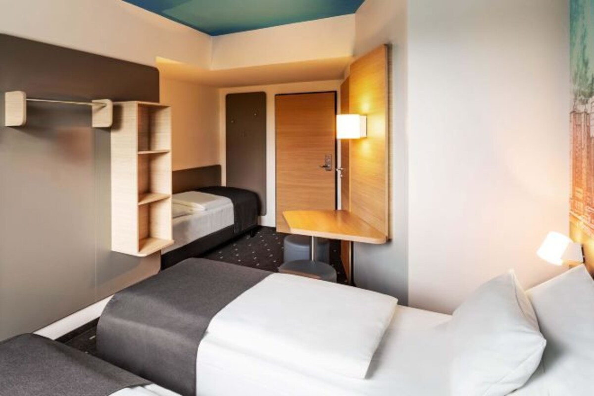 A hotel room with a bed, a bedside table, a lamp, and a wardrobe.