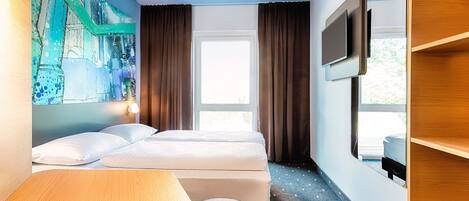 A hotel room with two beds, a desk, a TV, and a large window.