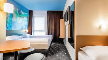 A hotel room with two beds, a desk, and a chair.