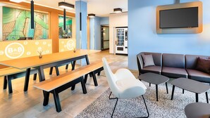 A modern hotel lobby with a reception desk, seating area, and vending machine. - B&B Hotel Chemnitz (Chemnitz)