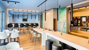 A modern bar area with a long counter, seating with stools, and a coffee machine. - B&B Hotel Chemnitz (Chemnitz)