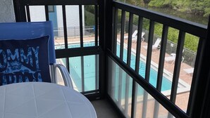 Ein Balkon mit Blick auf einen Swimmingpool und umliegendes Grün.