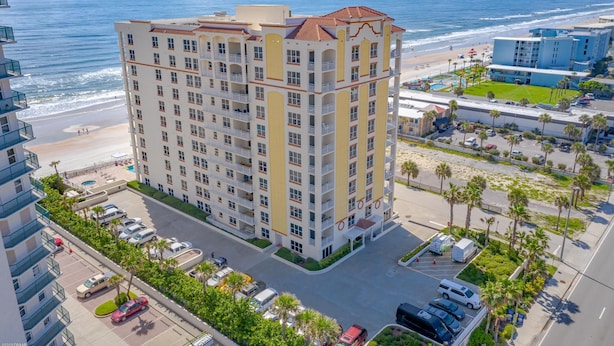 A multi-story hotel with a central courtyard, parking, and a view of the beach and ocean.