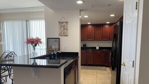 A kitchen with wooden cabinets, a black refrigerator, and a central island with a sink.
